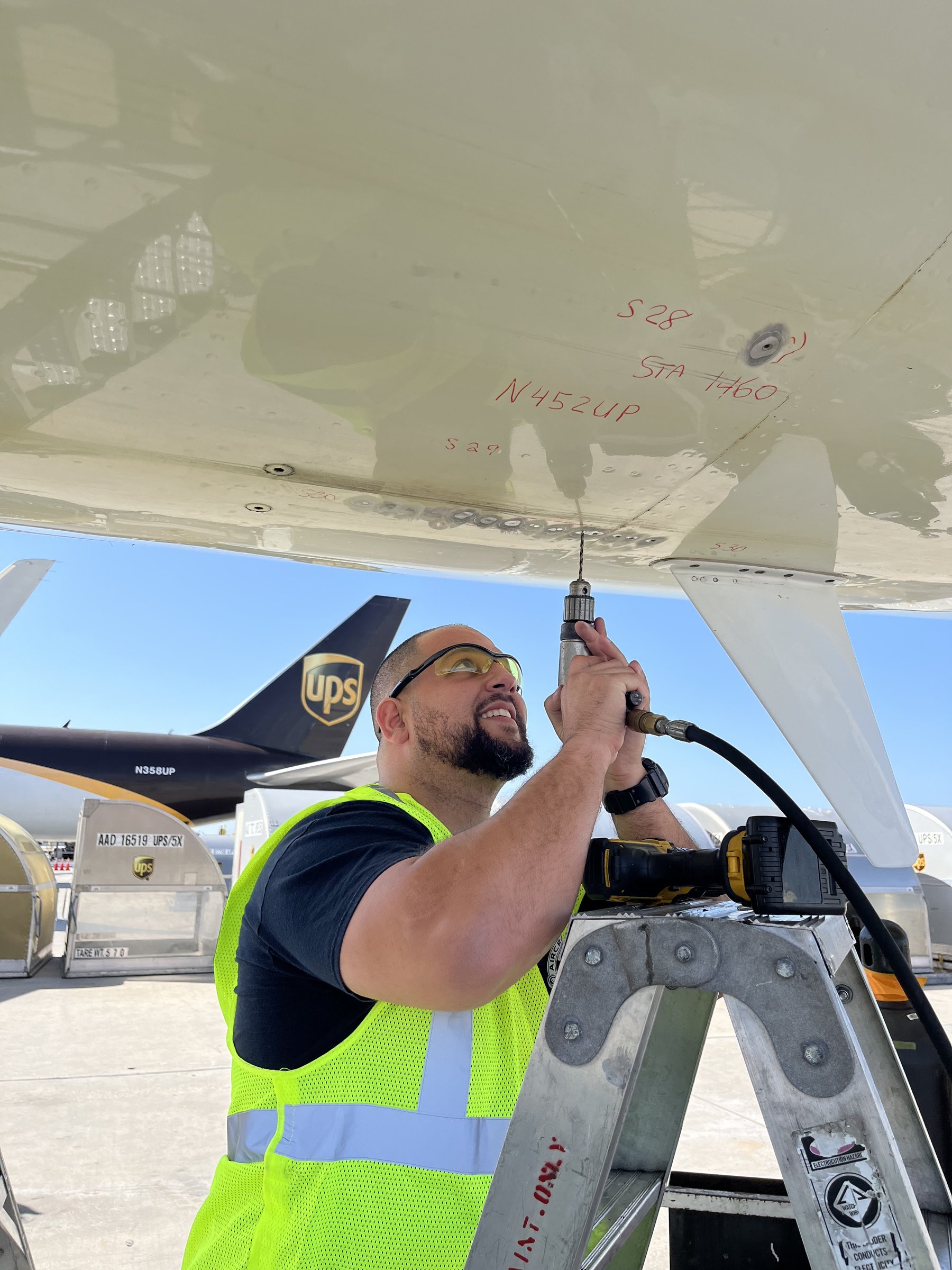 Carlos performing aircraft sheet metal work under the wing of a UPS cargo aircraft